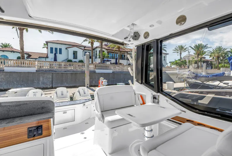  Yacht Photos Pics 2023 Boston Whaler 405 Conquest interior with seating and table, docked near luxury homes.