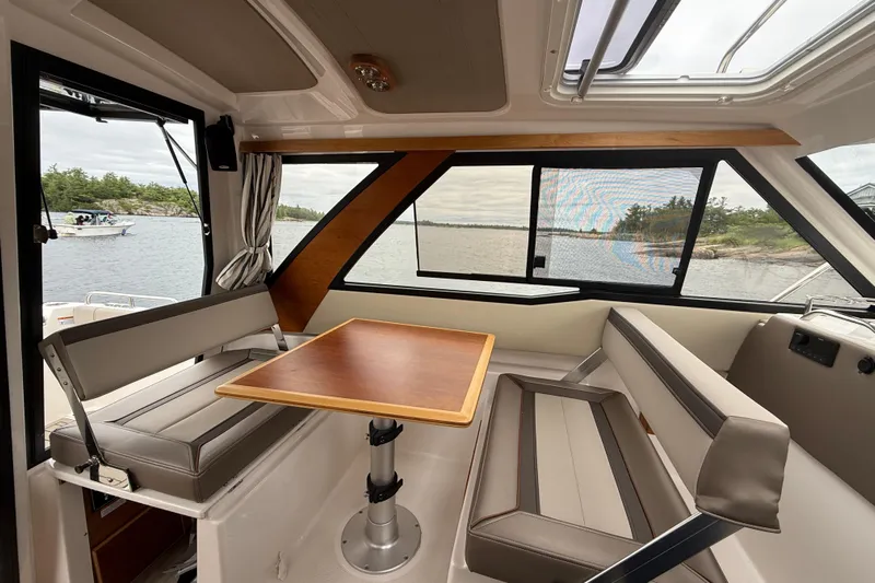  Yacht Photos Pics Interior of 2023 Cutwater C-248 Coupe boat with seating and table, overlooking a scenic water view.