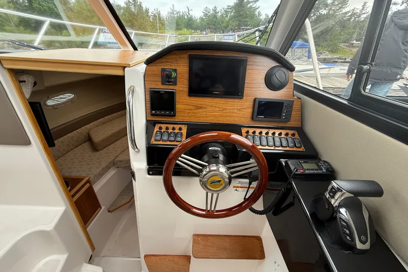  Yacht Photos Pics 2023 Cutwater C-248 Coupe helm with wood accents, steering wheel, and navigation controls.