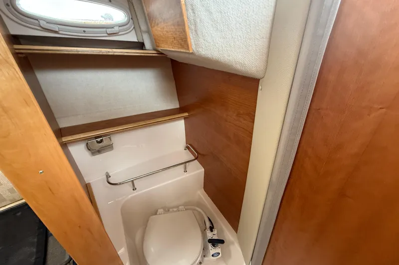  Yacht Photos Pics 2023 Cutwater C-248 Coupe bathroom interior with compact toilet and wooden shelving.