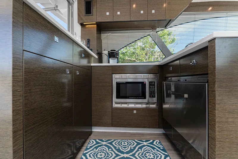 Lil' Darlin' Yacht Photos Pics Modern kitchen interior of 2018 Cruisers Yachts 50 Cantius with wood cabinetry and appliances.