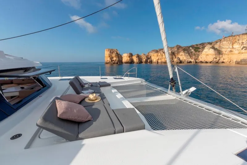  Yacht Photos Pics 2024 Fountaine Pajot Catamaran Elba 45 with sunbathing area, scenic coastal view.