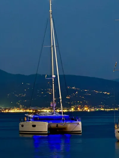  Yacht Photos Pics 2024 Fountaine Pajot Catamaran Elba 45 illuminated at night on calm waters.