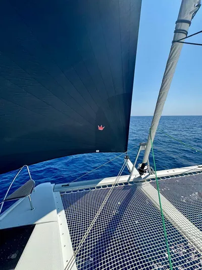  Yacht Photos Pics 2024 Fountaine Pajot Catamaran Elba 45 sailing on open sea, featuring netted deck and sail.