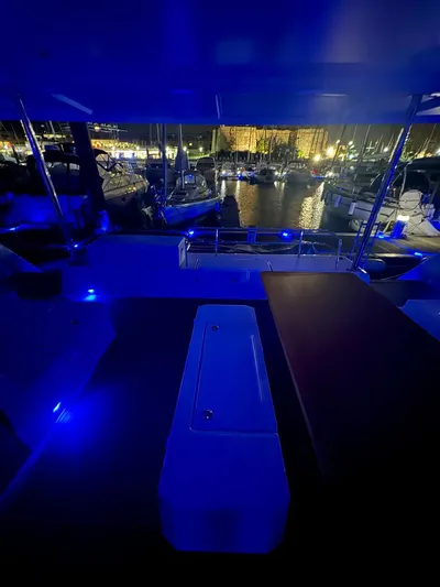  Yacht Photos Pics 2024 Fountaine Pajot Catamaran Elba 45 with blue ambient lighting at night in a marina.