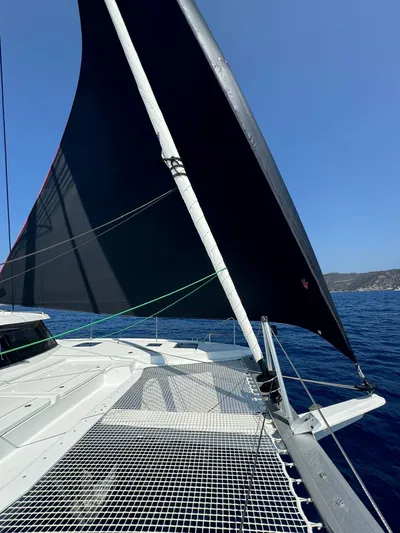  Yacht Photos Pics 2024 Fountaine Pajot Catamaran Elba 45 sailing on open sea with black sail.