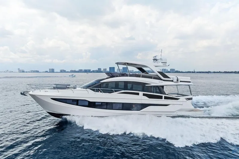 Triple T Yacht Photos Pics 2022 Galeon 640 Fly yacht cruising on open water with city skyline backdrop.
