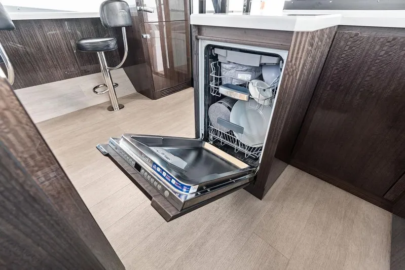Triple T Yacht Photos Pics Open dishwasher in 2022 Galeon 640 Fly yacht kitchen, featuring modern cabinetry and seating.
