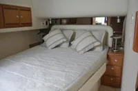 Luxurious bedroom interior of 2007 Cabo 43 FB yacht with cozy bedding and wooden cabinets.
