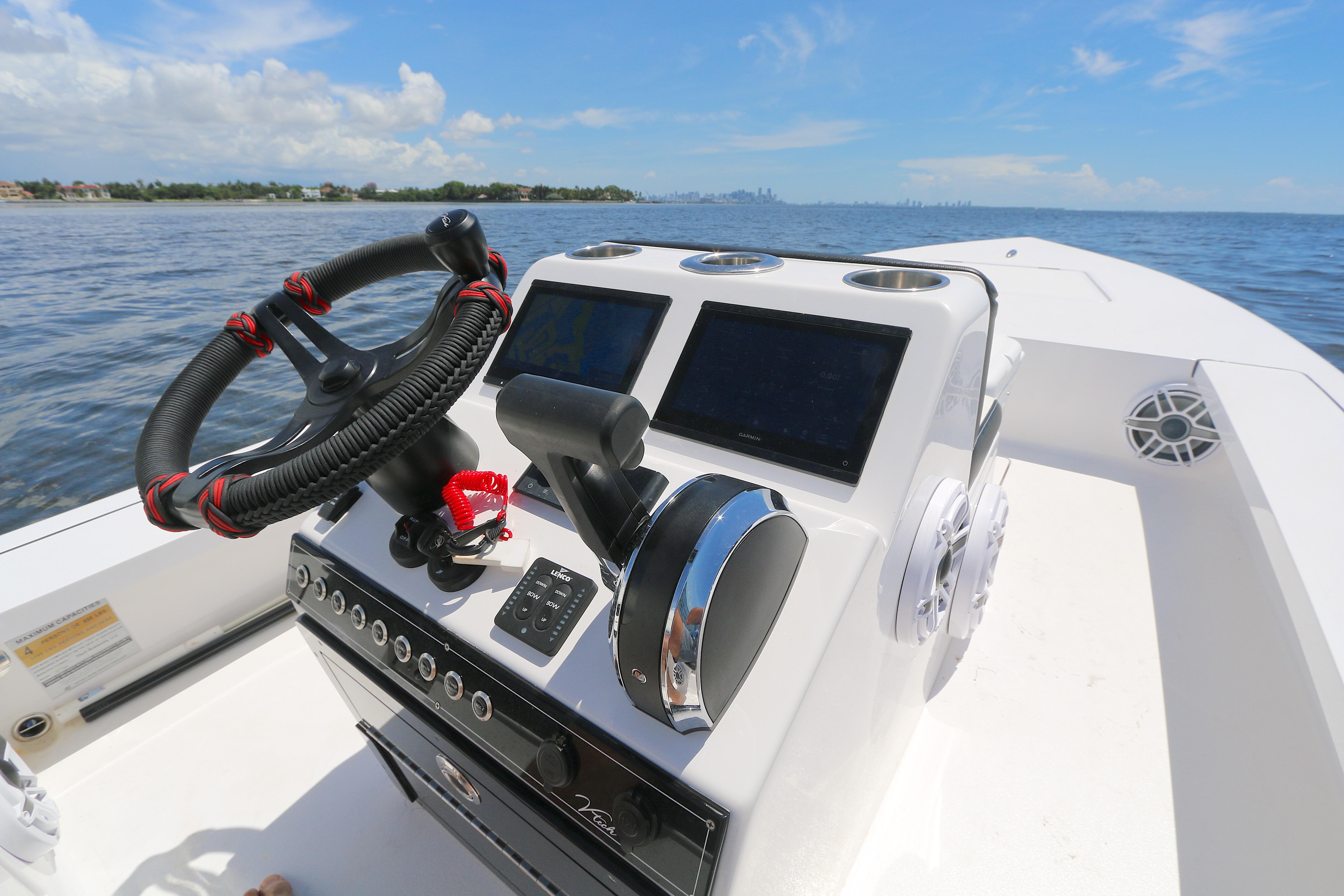 Boat dashboard with steering wheel and controls, Vtech 18 model, 2024, on open water.