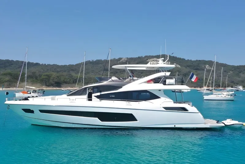 Sarahlisa Yacht Photos Pics Luxurious 2015 Sunseeker 75 yacht anchored in clear blue waters, surrounded by scenic coastline.