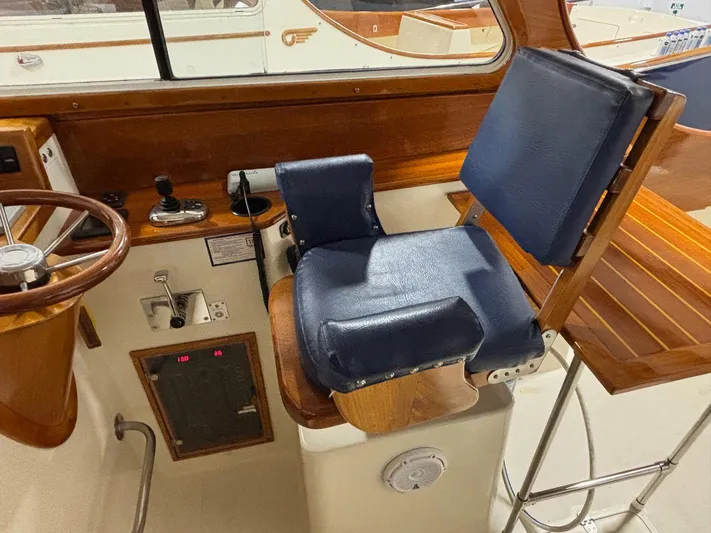 Celebration Yacht Photos Pics Helm station of 2002 Hinckley Picnic Boat 36 with blue seat and wooden accents.