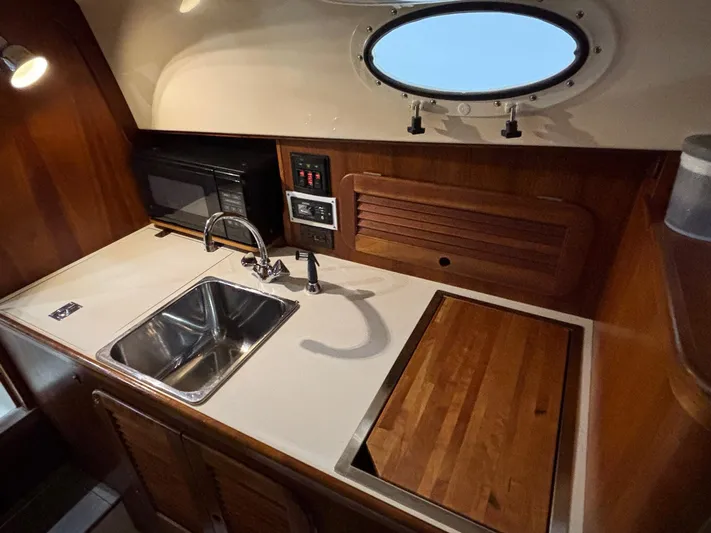 Celebration Yacht Photos Pics Compact galley in 2002 Hinckley Picnic Boat 36 with sink, cutting board, and porthole window.