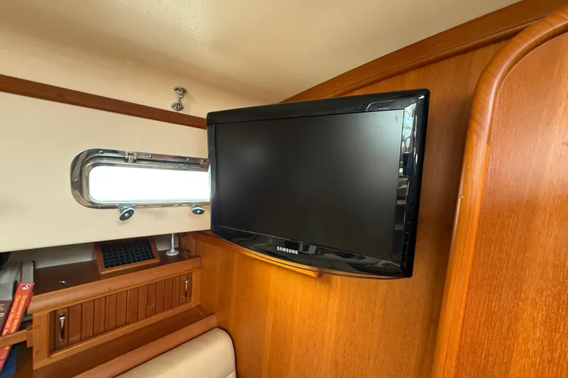Pelican Yacht Photos Pics Flat-screen TV in 2008 Island Packet 370 yacht interior, wooden paneling, and porthole window.