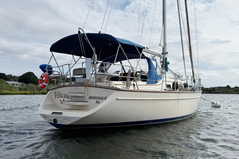Pelican Yacht Photos Pics 2008 Island Packet 370 sailboat anchored on calm water with blue canopy.