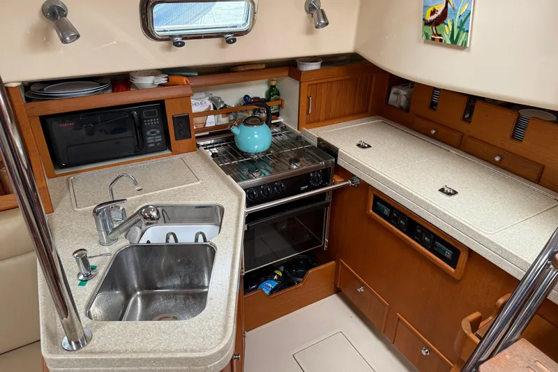 Pelican Yacht Photos Pics Compact kitchen in a 2008 Island Packet 370 sailboat with sink, stove, and microwave.