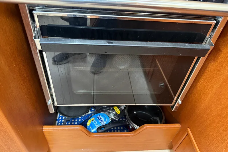 Pelican Yacht Photos Pics 2008 Island Packet 370 galley with oven and storage, featuring cleaning supplies and cookware.