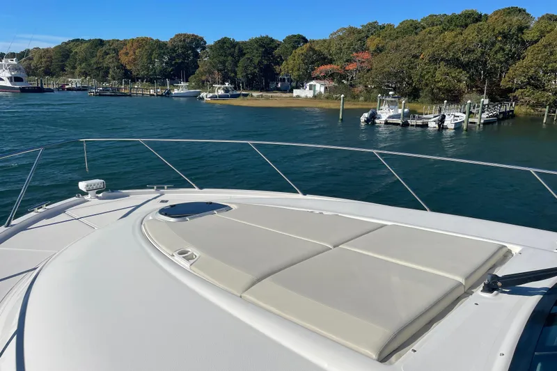 Bar Dog Yacht Photos Pics Luxurious 2020 Tiara 53C yacht with sunbathing deck, docked near scenic shoreline.