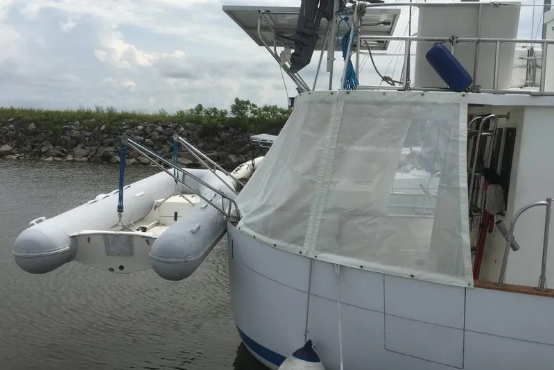  Yacht Photos Pics 1997 Willard Marine 40 Pilothouse Trawler with dinghy, docked by rocky shoreline.
