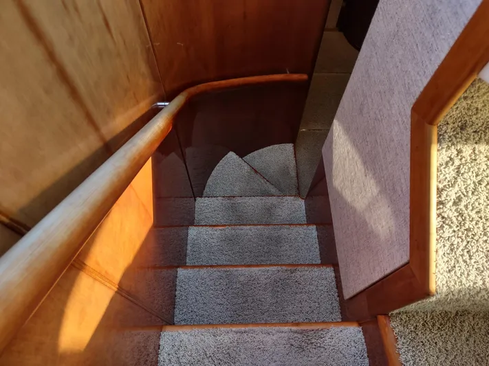 F66 Yacht Photos Pics Staircase inside a 1997 Fairline 66 yacht with wooden handrails and carpeted steps.
