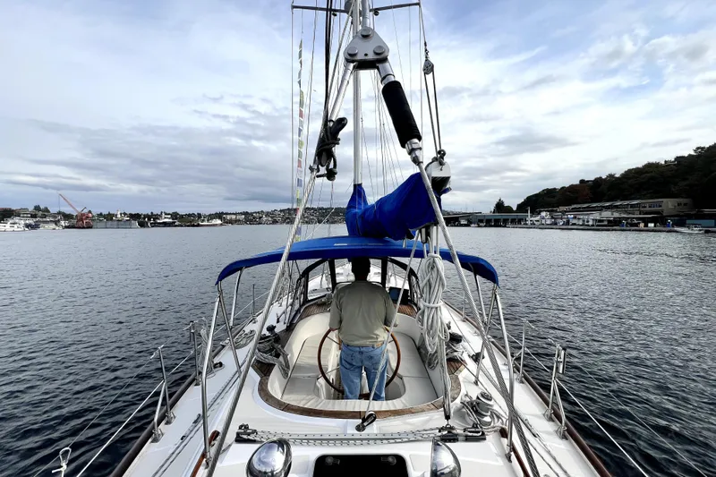  Yacht Photos Pics 1989 Taswell 43 sailboat on calm waters, featuring a blue canopy and scenic harbor view.