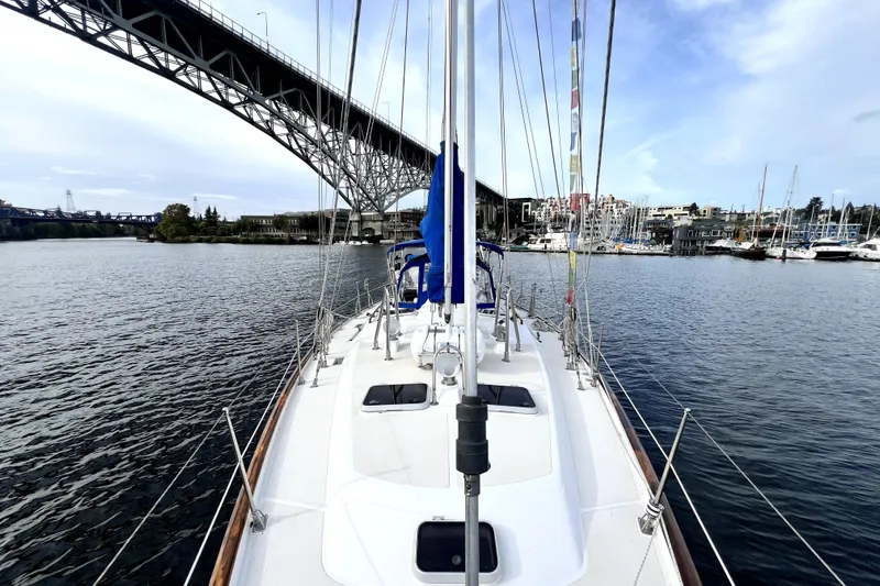  Yacht Photos Pics 1989 Taswell 43 sailboat under bridge, calm waters, marina in background.