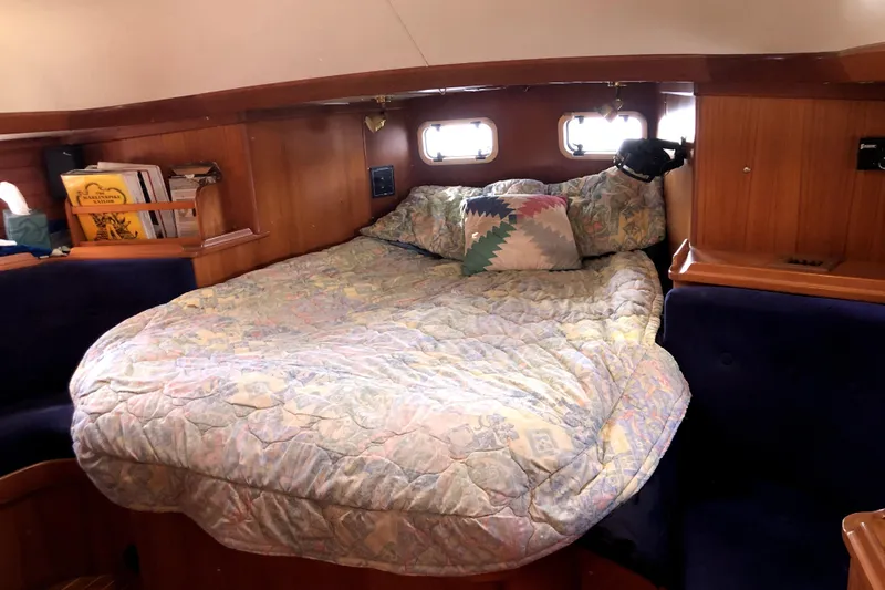  Yacht Photos Pics Cozy cabin interior of 1989 Taswell 43 sailboat with bed and wooden shelves.