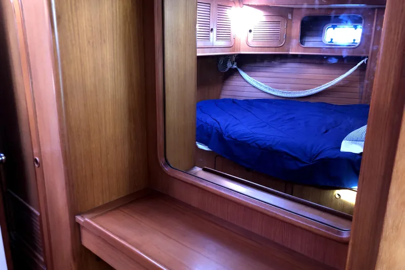  Yacht Photos Pics Cozy cabin interior of 1989 Taswell 43 sailboat with wooden finish and blue bedding.