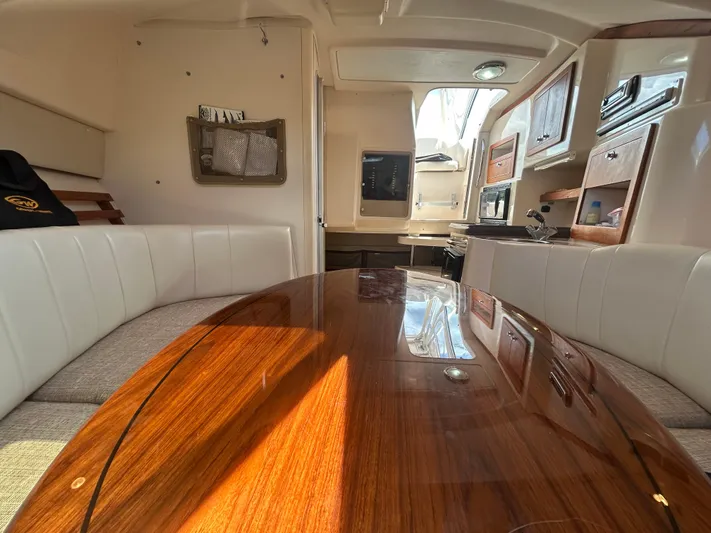 She Bot It II Yacht Photos Pics Interior of 2007 Grady-White Express 305 boat with polished wood table and white seating.
