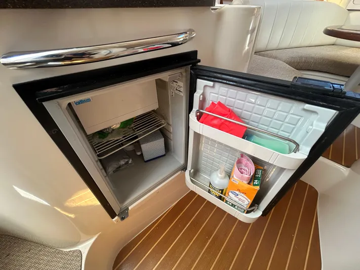 She Bot It II Yacht Photos Pics Open mini fridge on 2007 Grady-White Express 305 boat, showing interior contents and wooden flooring.