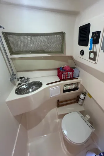 She Bot It II Yacht Photos Pics 2007 Grady-White Express 305 boat bathroom with sink, toilet, and storage basket.