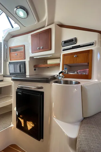 She Bot It II Yacht Photos Pics 2007 Grady-White Express 305 cabin interior with kitchenette, featuring sink, fridge, and storage cabinets.