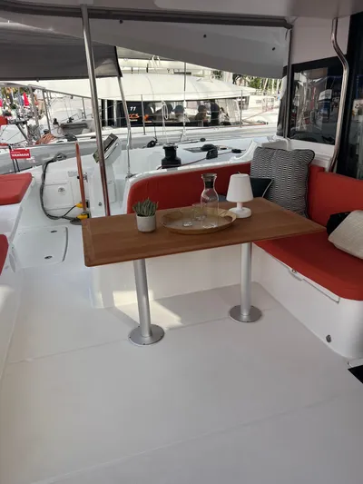  Yacht Photos Pics 2024 Excess 14 yacht interior with dining area, red seating, and wooden table.