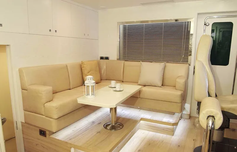  Yacht Photos Pics Luxurious Bandido 75 yacht interior, featuring beige seating, table, and window blinds, 2012 model.