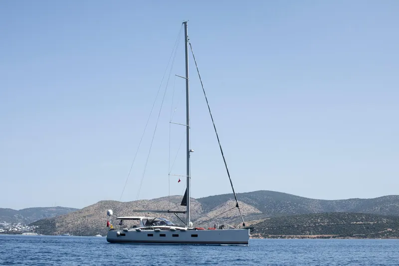  Yacht Photos Pics 2020 Jeanneau 64 yacht sailing on calm waters with scenic mountain backdrop.