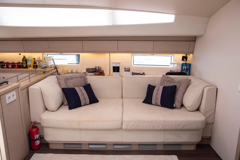  Yacht Photos Pics Luxurious interior of 2020 Jeanneau 64 yacht with elegant beige sofa and cushions.