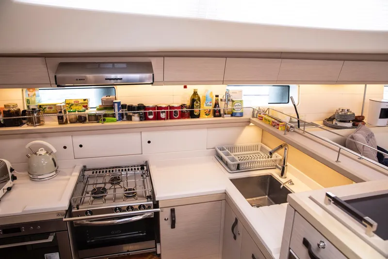  Yacht Photos Pics Modern kitchen in a 2020 Jeanneau 64 yacht with stove, sink, and storage.