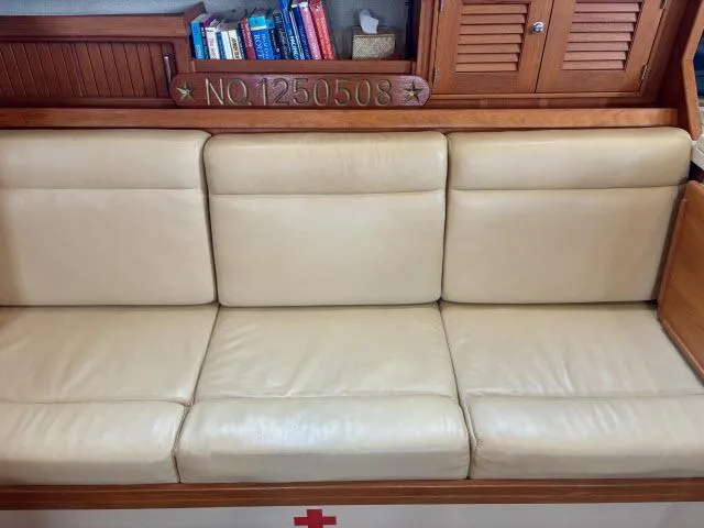 Pelican Yacht Photos Pics Cream leather seating in 2008 Island Packet 370 sailboat interior with books and wooden cabinetry.