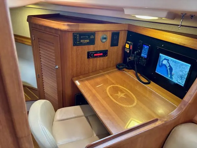 Pelican Yacht Photos Pics Navigation station of a 2008 Island Packet 370 sailboat with wood finish and electronic equipment.