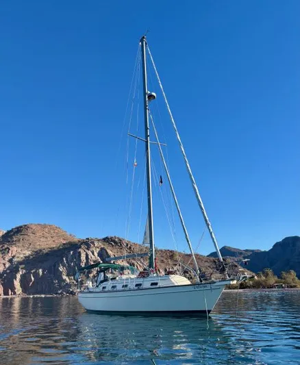 Pelican Yacht Photos Pics 2008 Island Packet 370 sailboat on calm water with mountainous backdrop.