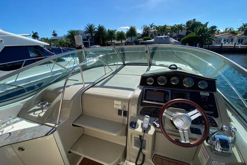  Yacht Photos Pics 2012 Sea Ray 330 Sundancer helm with steering wheel and control panel, docked by waterfront homes.