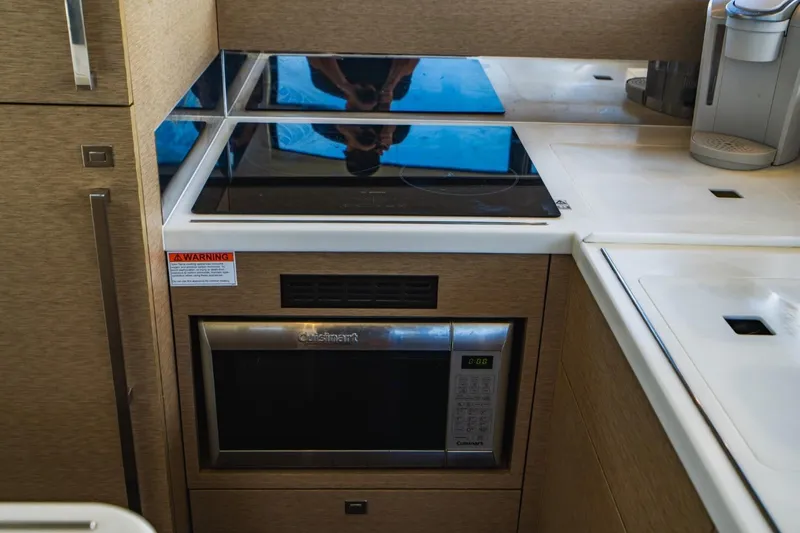  Yacht Photos Pics Modern kitchen area in a 2018 Prestige 500S yacht, featuring a stovetop and microwave.