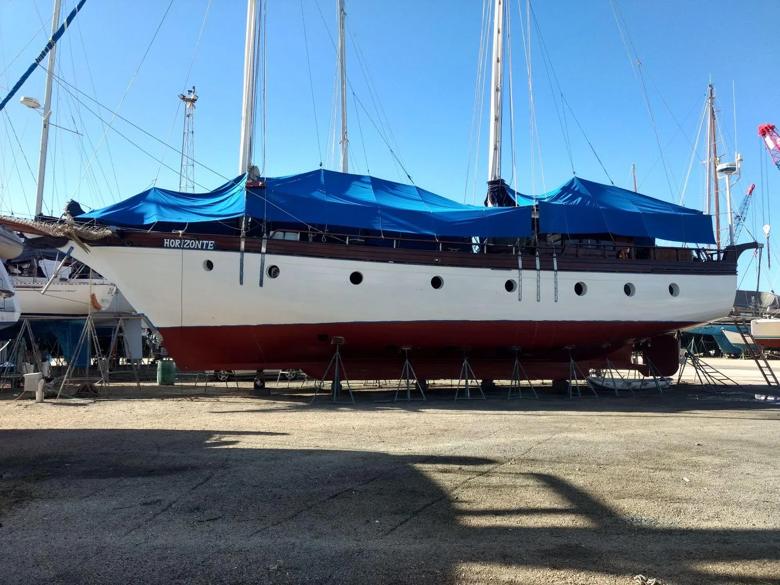 Custom 1991 Horacio Carabelli Schooner with blue tarps, docked on land.