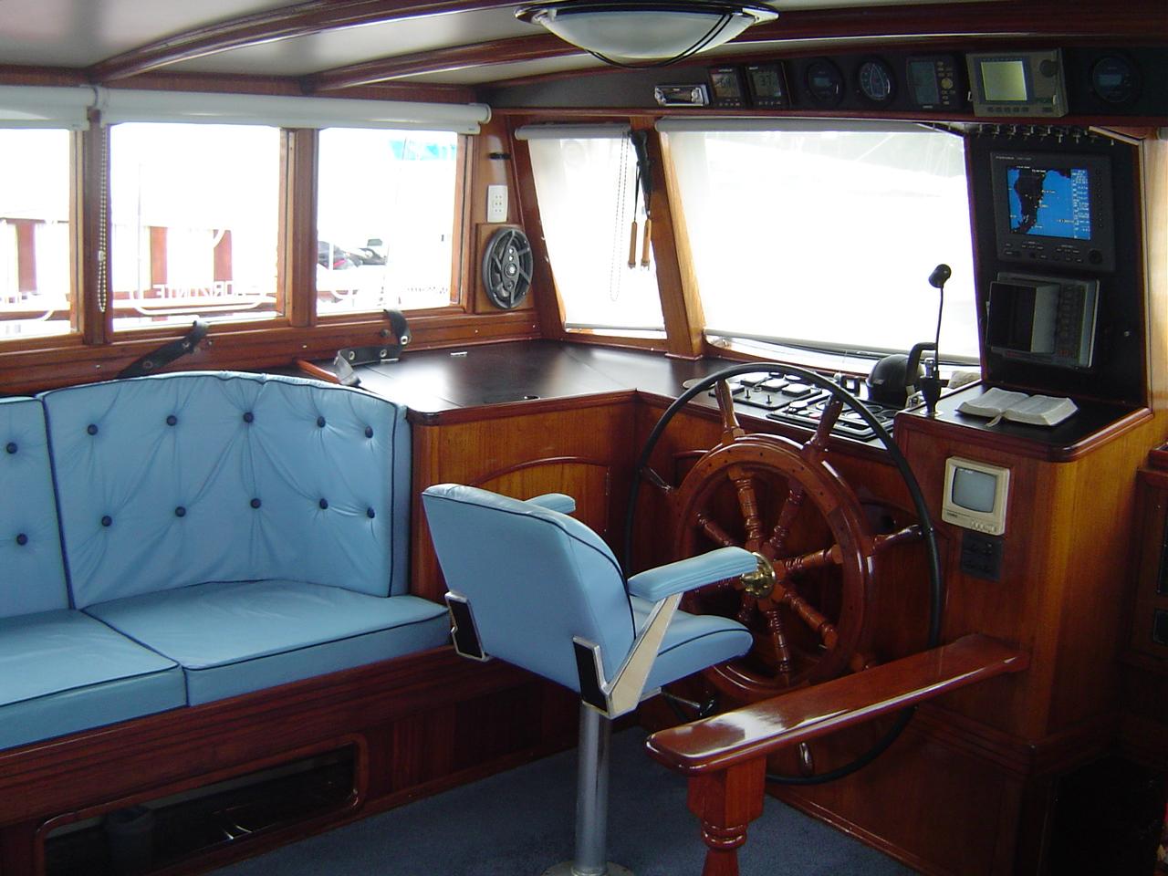 Interior of 1991 Custom Horacio Carabelli Schooner with blue seating and wooden steering wheel.
