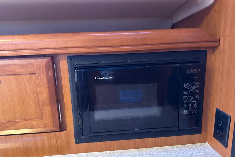 Murrelet Yacht Photos Pics Built-in microwave in 2009 Hunter 38 yacht kitchen, featuring wooden cabinetry.