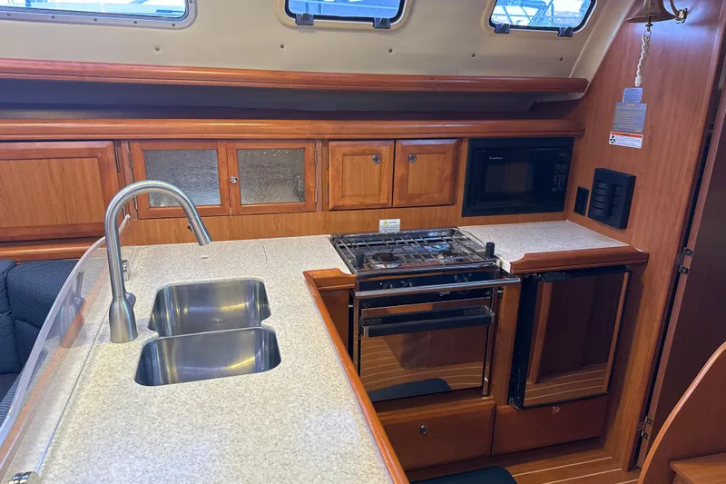 Murrelet Yacht Photos Pics Interior of a 2009 Hunter 38 yacht kitchen with stove, sink, and wooden cabinets.