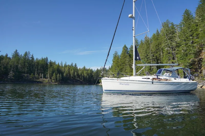 Murrelet Yacht Photos Pics Sailboat "Murrelet" on calm water, surrounded by lush forest, under clear blue sky. Hunter 38, 2009.