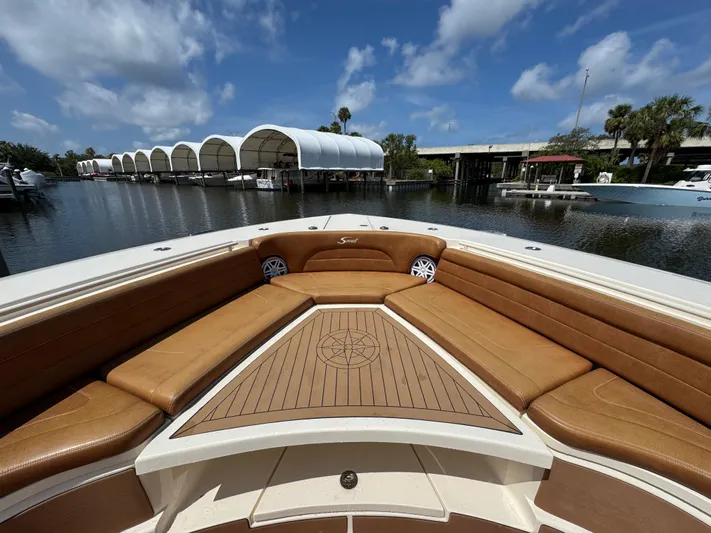  Yacht Photos Pics 2018 Scout 420 LXF boat with tan seating and wooden deck, docked under a blue sky.