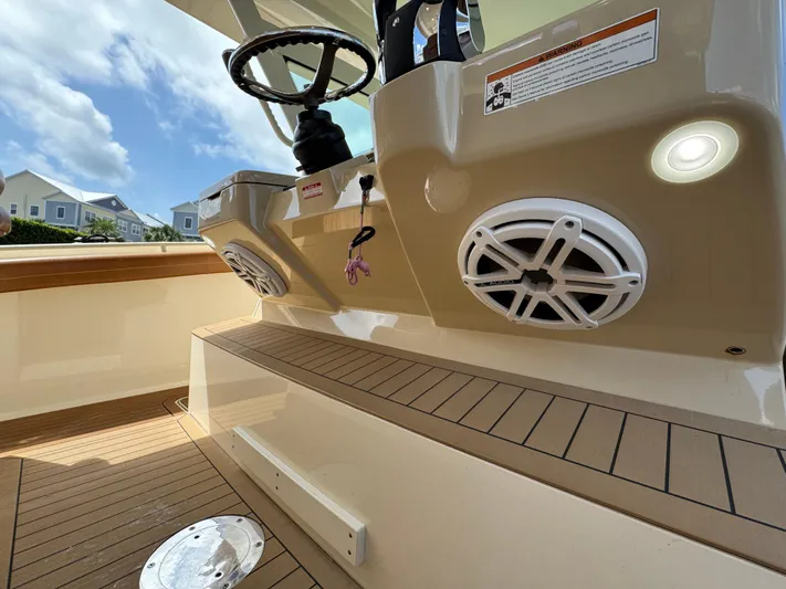  Yacht Photos Pics 2018 Scout 420 LXF boat interior with steering wheel and speakers, featuring teak flooring.
