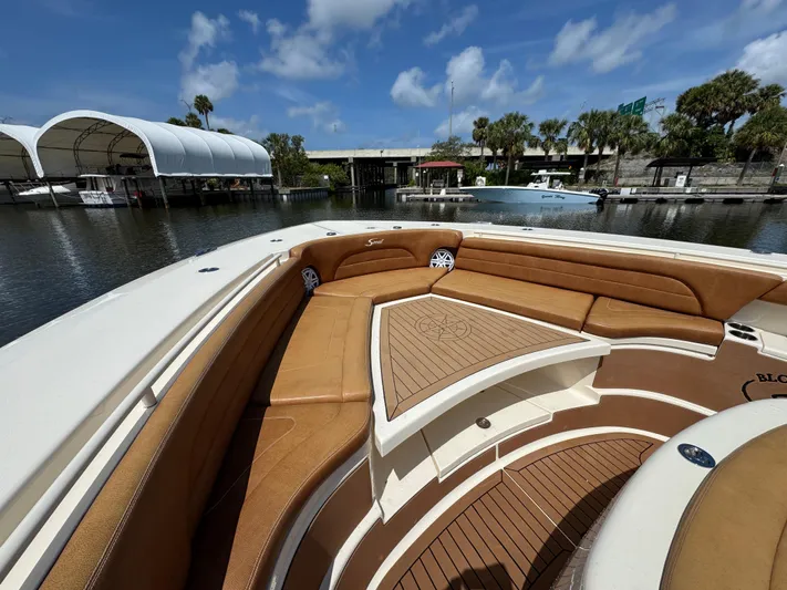  Yacht Photos Pics 2018 Scout 420 LXF boat with tan seating and wooden deck, docked by a marina.